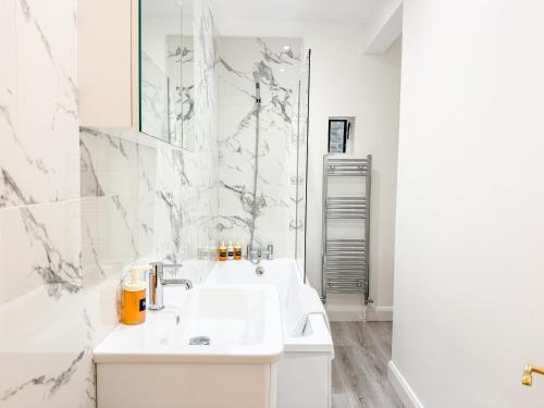 a white bathroom with two sinks and a mirror at Comfortable 3-Bed House near Canterbury Centre in Canterbury