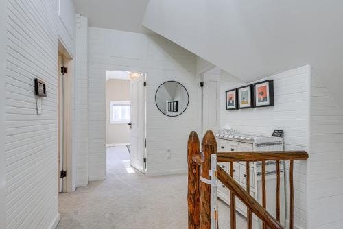 a hallway with white walls and a staircase with a mirror at Charming Jaffrey Cottage with Deck and Grill! in Jaffrey