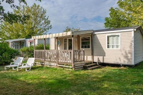 a tiny house with a porch and two chairs at ZEcamping 5 étoiles familial animaux acceptés in Sainte-Catherine-de-Fierbois