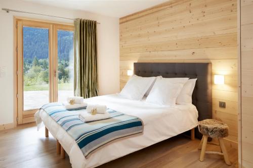 une chambre avec un grand lit et une grande fenêtre dans l'établissement Marmotte Mountain Eco Lodge, à Chamonix-Mont-Blanc