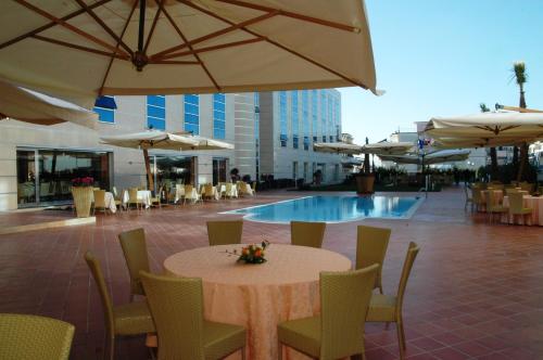 una mesa y sillas con sombrillas y una piscina en Hotel San Mauro, en Casalnuovo di Napoli