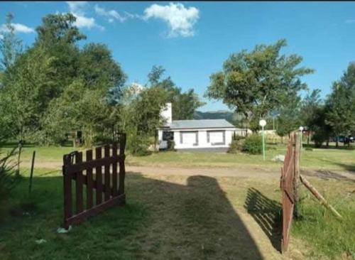 a wooden fence in a field with a building at El Atardecer in Villa Giardino