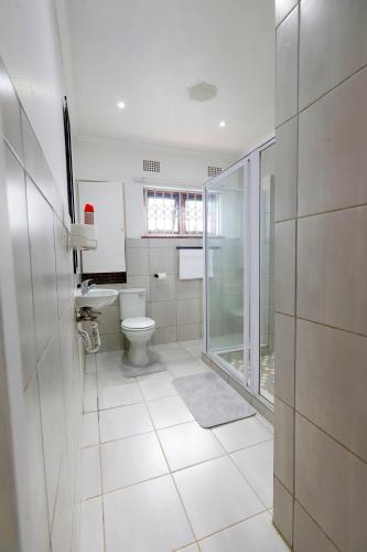 a white bathroom with a toilet and a window at Riveria Guest Lodge and SPA in East London