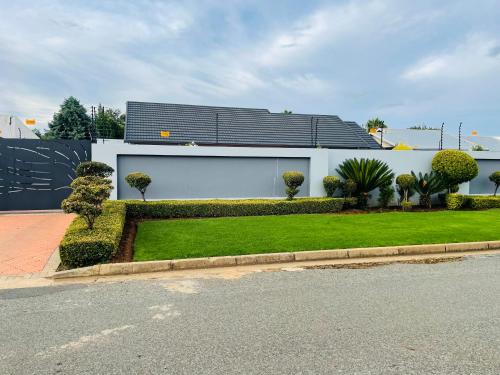 een wit huis met een groen gazon ervoor bij Loreho boutique in Mahikeng