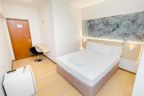 a bedroom with a large white bed and a desk at Hotel & Restaurante Paraíso Ponte Nova - Ponte Nova - MG in Ponte Nova