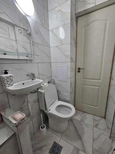 a white bathroom with a toilet and a sink at BOMBA Apartman in Târgu Secuiesc