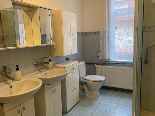 a bathroom with two sinks and a toilet at Uzdrowiskowe Retro by LibertaRent in Szczawno-Zdrój