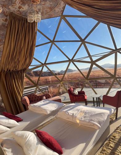 una stanza con quattro letti e una grande finestra di vetro di Desert Bedouin adventure a Wadi Rum