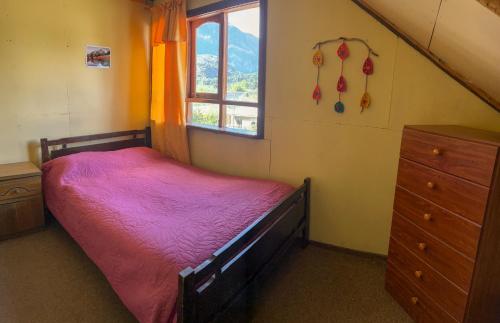 ein kleines Schlafzimmer mit einem Bett und einem Fenster in der Unterkunft Hospedaje La Cascada in Futaleufú