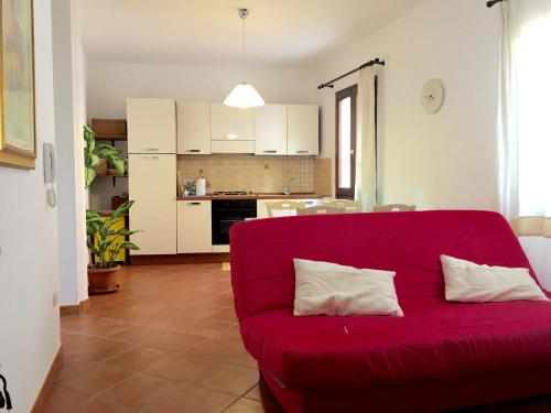 un sofá rojo en la sala de estar con cocina en La Colbula, en Castelsardo
