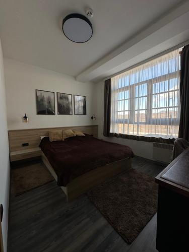 a bedroom with a bed and a large window at Mountain Hearth - Milmari Resort in Kopaonik