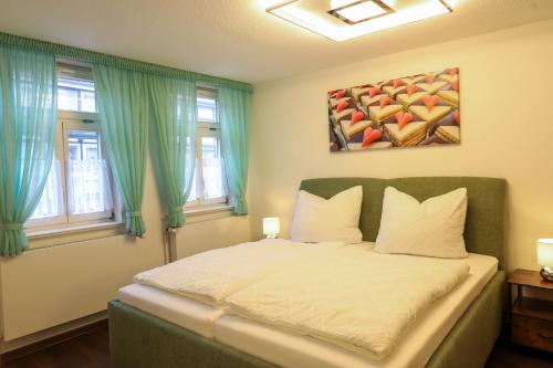 a bedroom with a bed with green curtains and a painting at Ferienwohnung Zum Alten Cafè in Neustadt