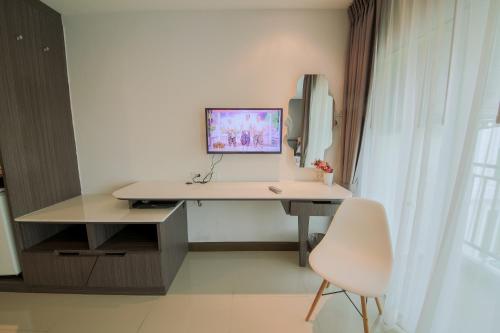 a desk with a computer and a chair in a room at The Sila Hotel in Si Racha