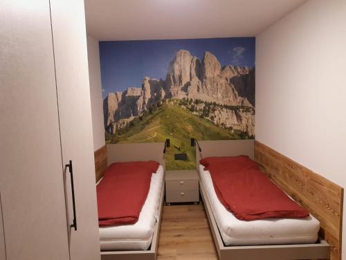 two beds in a room with a mountain mural at Casa Zena in Tesero