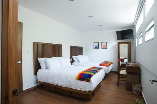 a bedroom with two beds with white sheets at La Casa del Mural - Suites Condesa in Mexico City