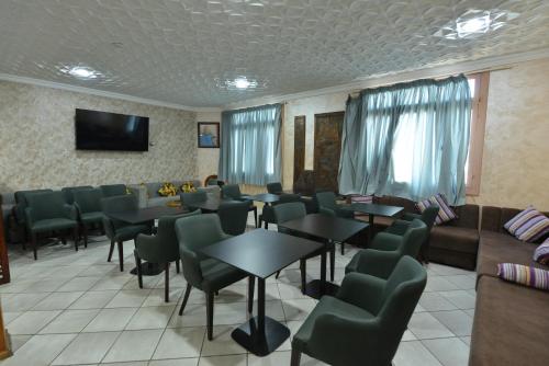 Una sala de espera con mesas y sillas y un televisor. en HOTEL VELLEDA, en Rabat