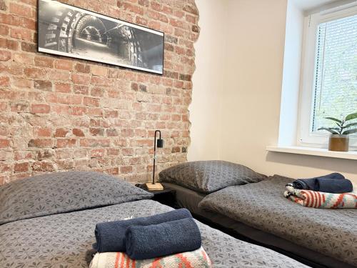 una camera da letto con due letti e un muro di mattoni di Apartament Kopalniok a Zabrze