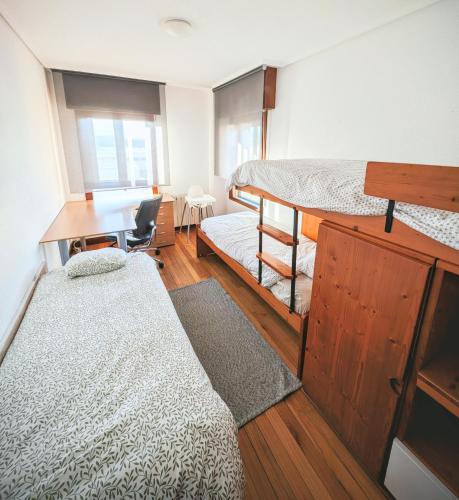 a dorm room with two beds and a desk and a table at Apartamento La Ballena 1 - Juan Vella in Santoña