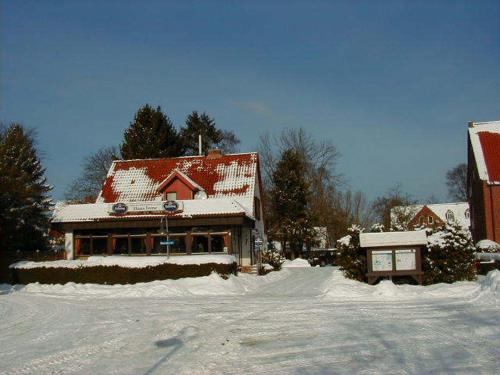 a house is covered in snow in a yard at Hotel Pension Haus Irene in Hohwacht