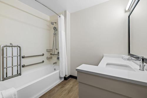 een witte badkamer met een wastafel en een bad bij Everhome Suites Rochester Greece in Rochester