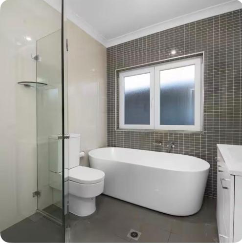 a bathroom with a tub and a toilet and a window at Lovely Duplex in Cabramatta West