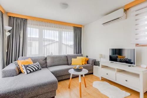a living room with a couch and a flat screen tv at Gezellige chalet in Lithse Ham in Lith