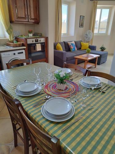 a dining room table with plates and wine glasses at Joseph 2, Charming Retreat with park views and close to the airport in Siġġiewi