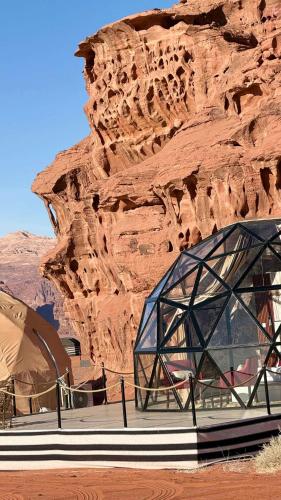 un edificio di vetro di fronte a una parete rocciosa di Wadi Rum Bubble Dream a Wadi Rum
