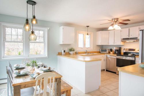 a kitchen with white cabinets and a wooden table at Minutes to Private Association in Eastham