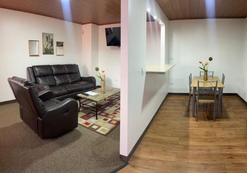 a living room with a leather couch and a table at Apartamento completo cerca del Aeropuerto y Parque Viva 5 personas in Guácima