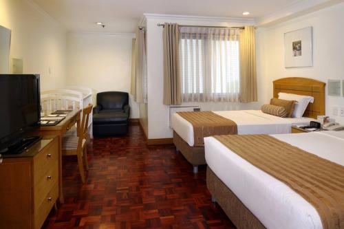 a hotel room with two beds and a flat screen tv at City Garden Suites Manila in Manila