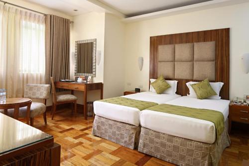 a hotel room with a large bed and a desk at City Garden Suites Manila in Manila