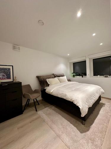 a bedroom with a bed and a chair and two windows at Nordic Panorama in Tromsø