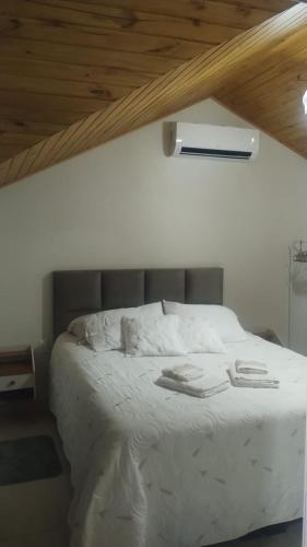 a white bed in a room with a wooden ceiling at Ametista Apartment in Nova Petrópolis