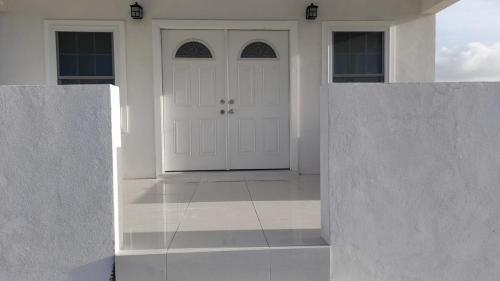 Bella Blus Villa的一栋白色的房子，有两扇白色大门和一个庭院。