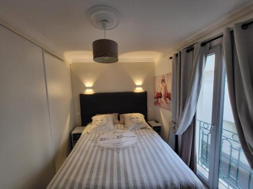 a bedroom with a bed with striped sheets and a window at Remblai des Sables d'Olonne - 2 chambres - parking et piscine in Les Sables-d'Olonne
