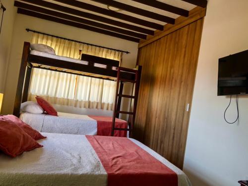 a bedroom with two bunk beds and a flat screen tv at Casa Chute in Chinchiná