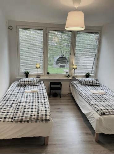 two beds in a room with two windows at Rymligt och härligt radhus i Göteborg in Gothenburg