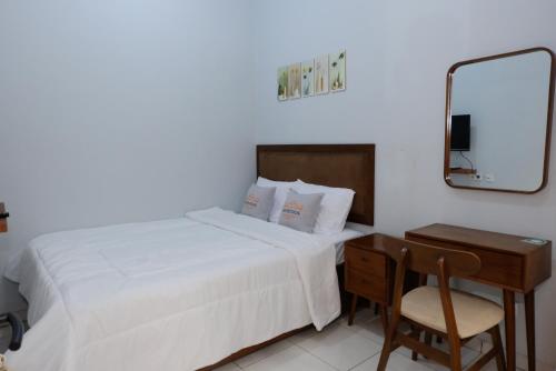 ein Schlafzimmer mit einem Bett, einem Schreibtisch und einem Spiegel in der Unterkunft Shoreside - Bukit Asri in Jepara