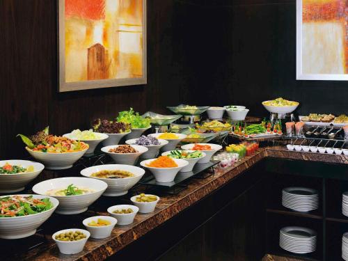 a buffet line with many bowls and plates of food at Mövenpick Hotel Apartments Al Mamzar Dubai in Dubai