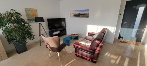 een woonkamer met een bank, een stoel en een tv bij La maison du saule in Yves