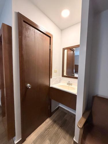 a bathroom with a wooden door and a sink at Hotel Mirage Diagonal in Matamoros