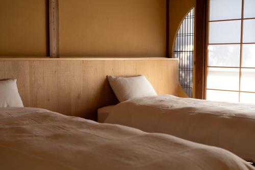 a bedroom with two beds and a window at 久乃家 in Matsue