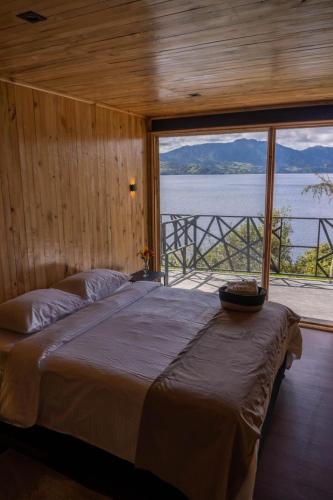 a bedroom with a large bed with a view of the water at Ecohotel Mauka in Pasto