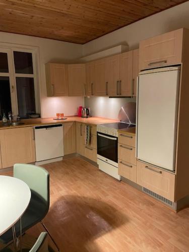 a kitchen with wooden cabinets and a white refrigerator at Stay in Graasten - surrounded by royal peace and history in Gråsten
