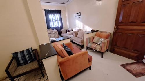 a living room with couches and chairs and a door at Appartement lumineux 2 pas à l'aéroport in Marrakech