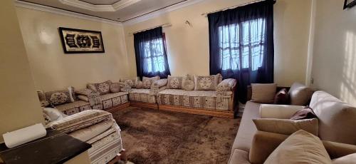 a living room with couches and chairs and windows at Appartement lumineux 2 pas à l'aéroport in Marrakech