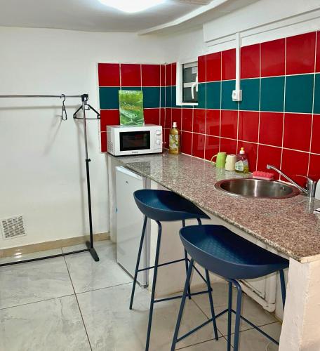 una cucina con un lavello e due sgabelli da bar blu di AZUR HOTEL a Saint-Denis
