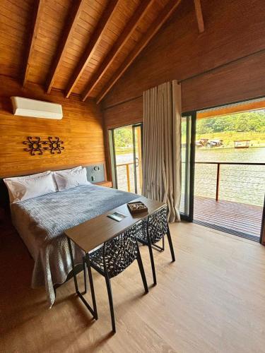 a bedroom with a bed and a table in it at Pousada reserva do J in Serra Negra