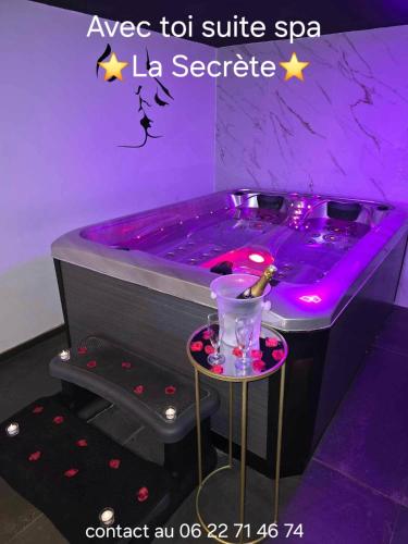 a purple bath tub with a table in a room at Avec toi suite spa La Secrète in Barlin